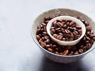 Whole Coffee beans in bowl on blue background