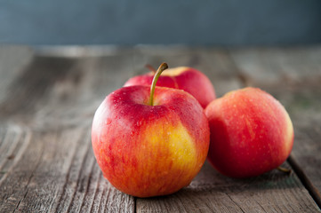 Close up fresh Ripe organic red apples with water drops on the rustic wooden table. Space for text. Selective focus. Autumn harvest concept. Vegetarian, vegan, healthy diet food.