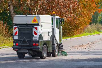 Street sweeper machine cleaning up the fallen leaves from the street