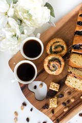 two cups of coffee with buns on the wooden cutting board