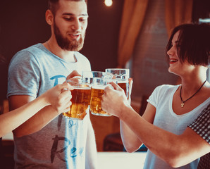 Friends toasting with glasses of light beer at the pub. Beautiful background of the Oktoberfest. A group of young people while relaxing at the bar. fine grain. Soft focus. Shallow DOF