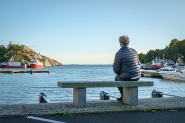 Woman sitting on bench in a fishing harbour