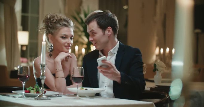 couple at the restaurant on the first date, take a selfie using a smartphone