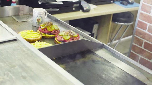 Hands of chef putting salad on a ready burger