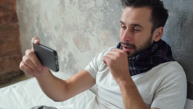 Positive minded sick man coughing while having video call