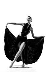 A beautiful athletic girl in a black dress is dancing