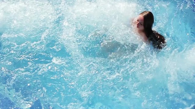 Young beautiful girl is swimming in the pool in the hot tub