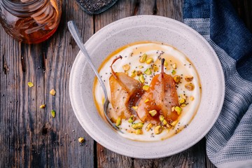 Healthy breakfast bowl: yogurt with caramelized pears, pistachios, honey and chia seeds