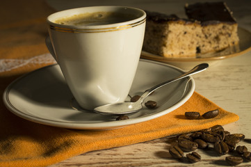 Coffee in a white cup. Spilled coffee beans. Sweet dessert on a plate of coffee. In the dark with side light and analog effect in retro - vintage style