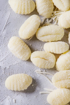 Raw uncooked potato gnocchi with flour and grated parmesan cheese over gray concrete background. Close up. Home cooking.