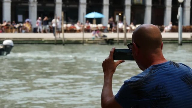 Man filming with his Samsung S6 a gondola in Venice Italy