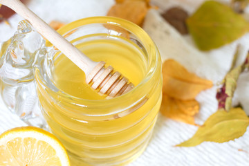Honey jar and lemon on white background