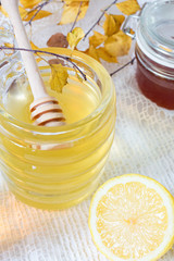 Honey jar and lemon on white background