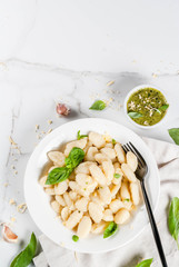 Italian food recipe, Healthy vegan dinner with potato gnocchi. With grated parmesan cheese, basil and pesto sauce. On white marble , copy space  top view