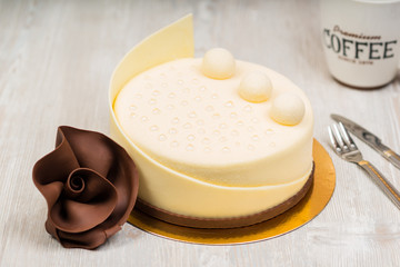 The white chocolate cake and rose with coffee on the table