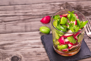 Glass of cucamelon and radish salad on wooden table with copy space