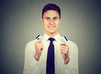 Happy debt free young man holding a credit card cut in two pieces