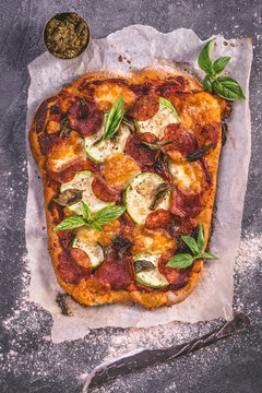 Rustic spicy salami, courgette and  mozzarella pizza with basil. Top view 