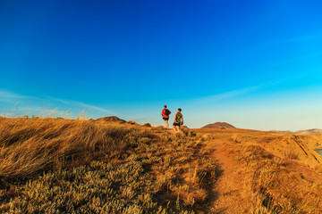 Two tourists walk across the hills.