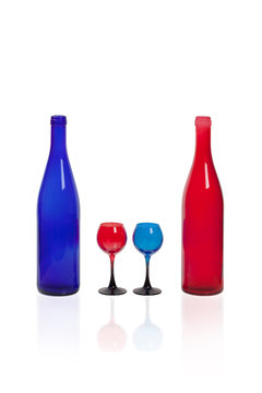 Blue and red bottle with glasses of the same color on a white background.