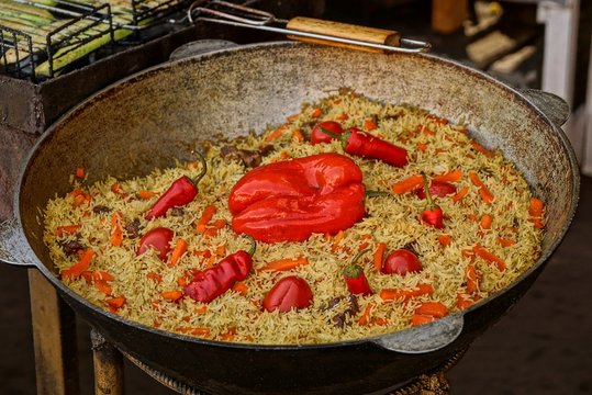 Плов из риса  кусков мяса и овощей в большом чане на кухне