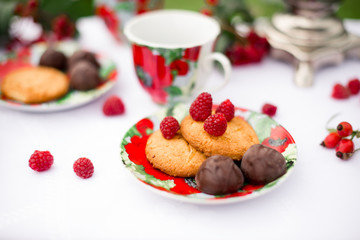 Самовар с чашками и десертом с малиной на столе в саду. Завтрак на природе 