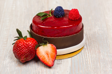 The chocolate glaze berry cake and strawberry on the white table