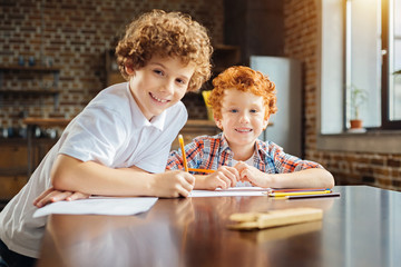 Cheerful boys grinning broadly for camera while drawing