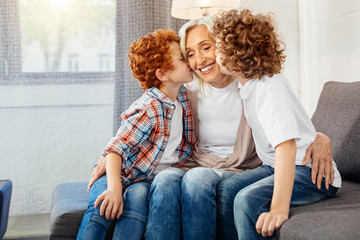 Elderly lady smiling while grandsons kissing her