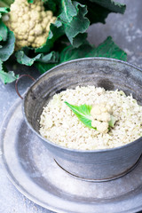 Cauliflower rice in metal bowl on grey background. Close up. Overhead. Shredded