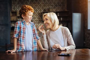 Fototapeta premium Thoughtful granny listening to music with grandson