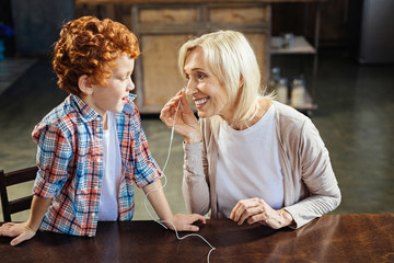 Redhead little boy sharing earphones with granny