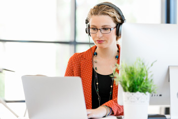 Young woman listening to the music while working on a computer