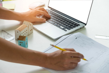 Architects are writing on the desk other hand uses a laptop.