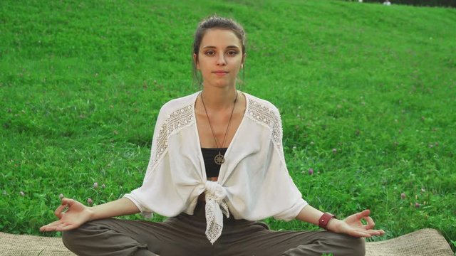 Young girl is doing the main pose of yoga called easy pose. She looks fresh and happy