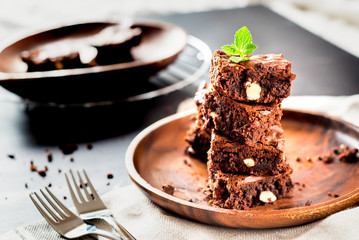 homemade chocolate brownies tower in a wooden plate on grey background