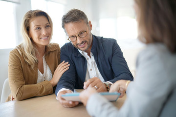 Mature couple meeting real-estate agent in office