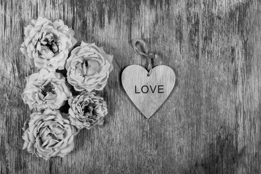 Dry withered roses and a heart on an old wooden background. Monochrome