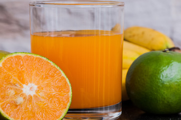 a glass of fresh juice and green mandarins