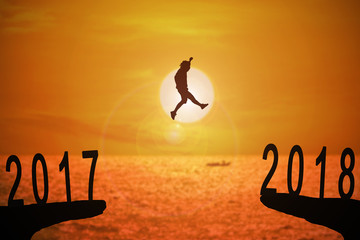 Plakat Silhouette of young man jumping between 2017 and 2018 years with beautiful sunset at the sea-concepts of news year and business target.