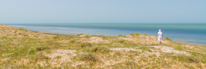 Bedouin in white robe overlooking the Atlantic ocean from dunes in Banc d Arguin National Park,...
