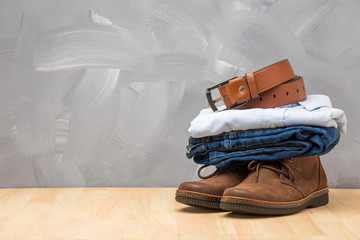 Asian vintage style men clothing and jeans and bag put on wooden table and loft concrete wall texture background.