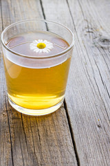 Cup of tea with chamomile flowers on rustic wooden background