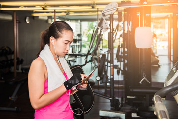 Fototapeta na wymiar Active girl using smartphone in fitness gym