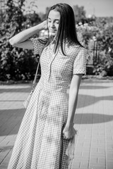 A young sweet woman dressed in a long dress in a blue cage enjoys this day in the garden on a warm sun. Young and beautiful 