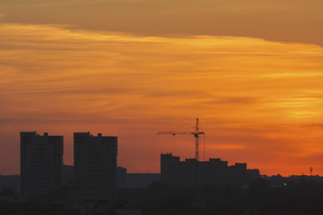 Fototapeta na wymiar Construction cranes near residential apartments - view on sunrise, horizontal