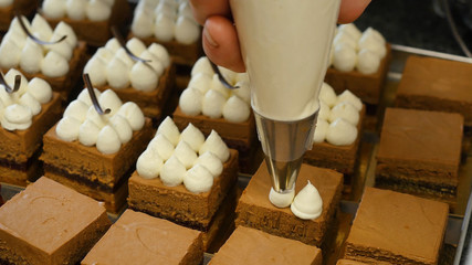 Cream being squeezed onto chocolate cakes. Squeezing the cream on the cake