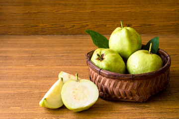 Fresh guava fruit in basket on wooden table background.