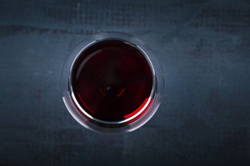 Pouring red wine into the glass against wooden background