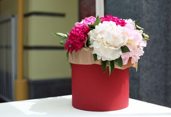 Gift box with beautiful peonies on table, outdoors